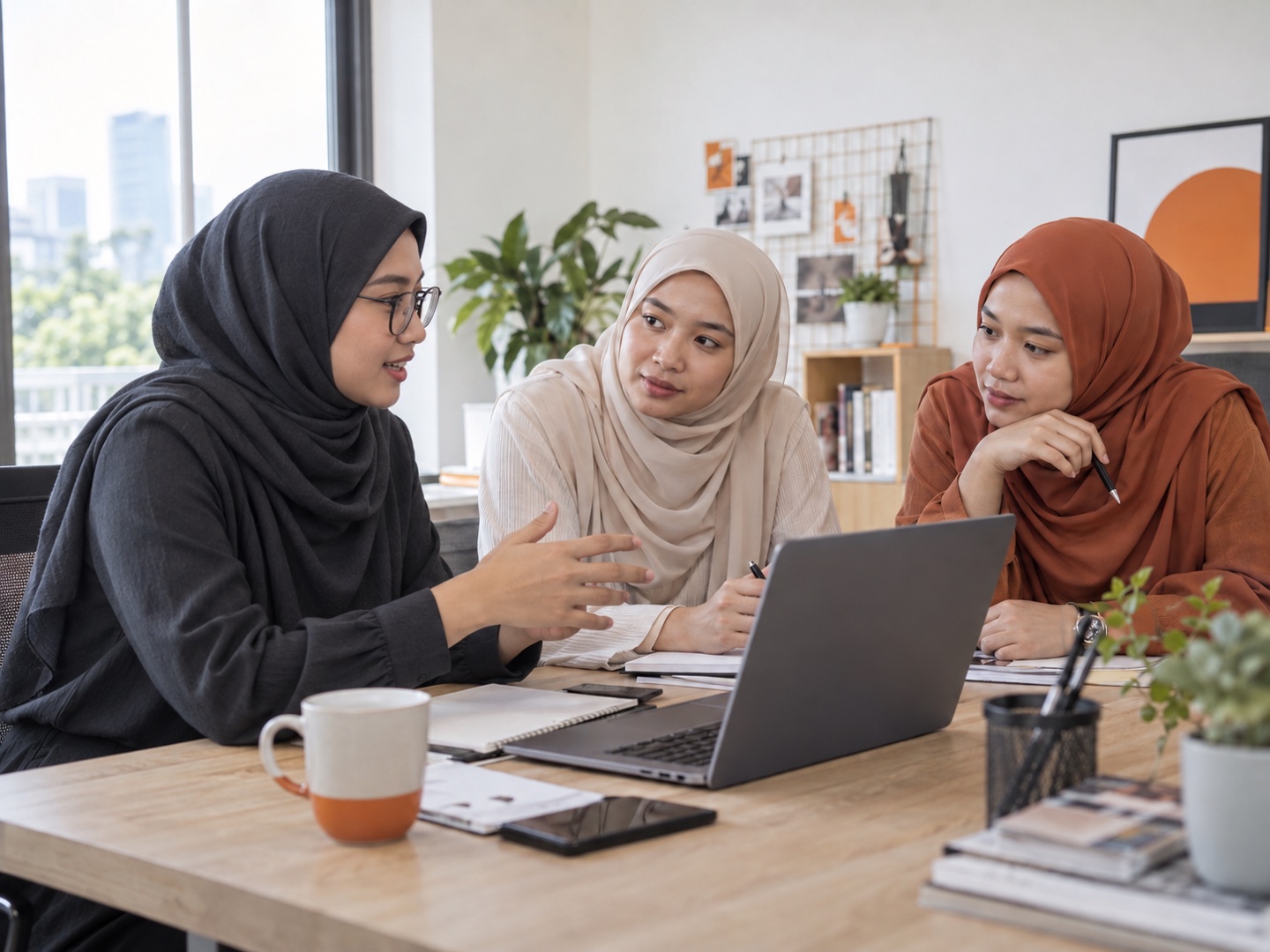 Tiga wanita Asia berhijab berbincang tentang kempen; wanita di kiri memakai cermin mata